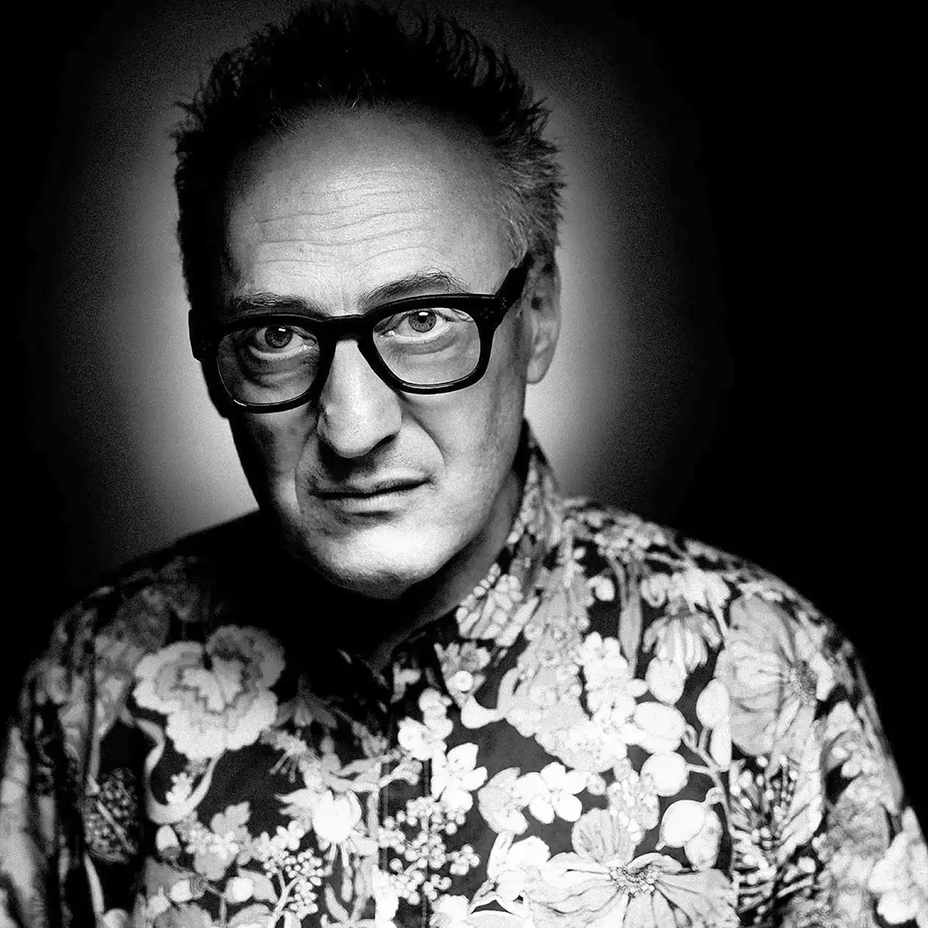 Black and white portrait of a man wearing glasses and a patterned shirt